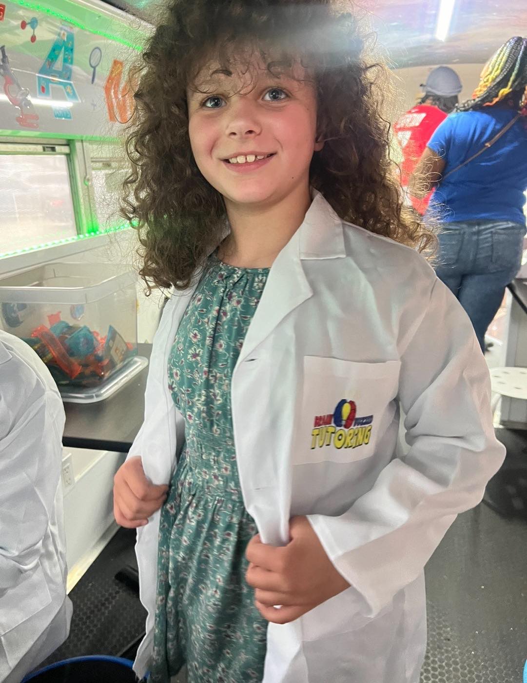 A student wearing a BrainBuzzed Tutoring lab coat aboard the bus