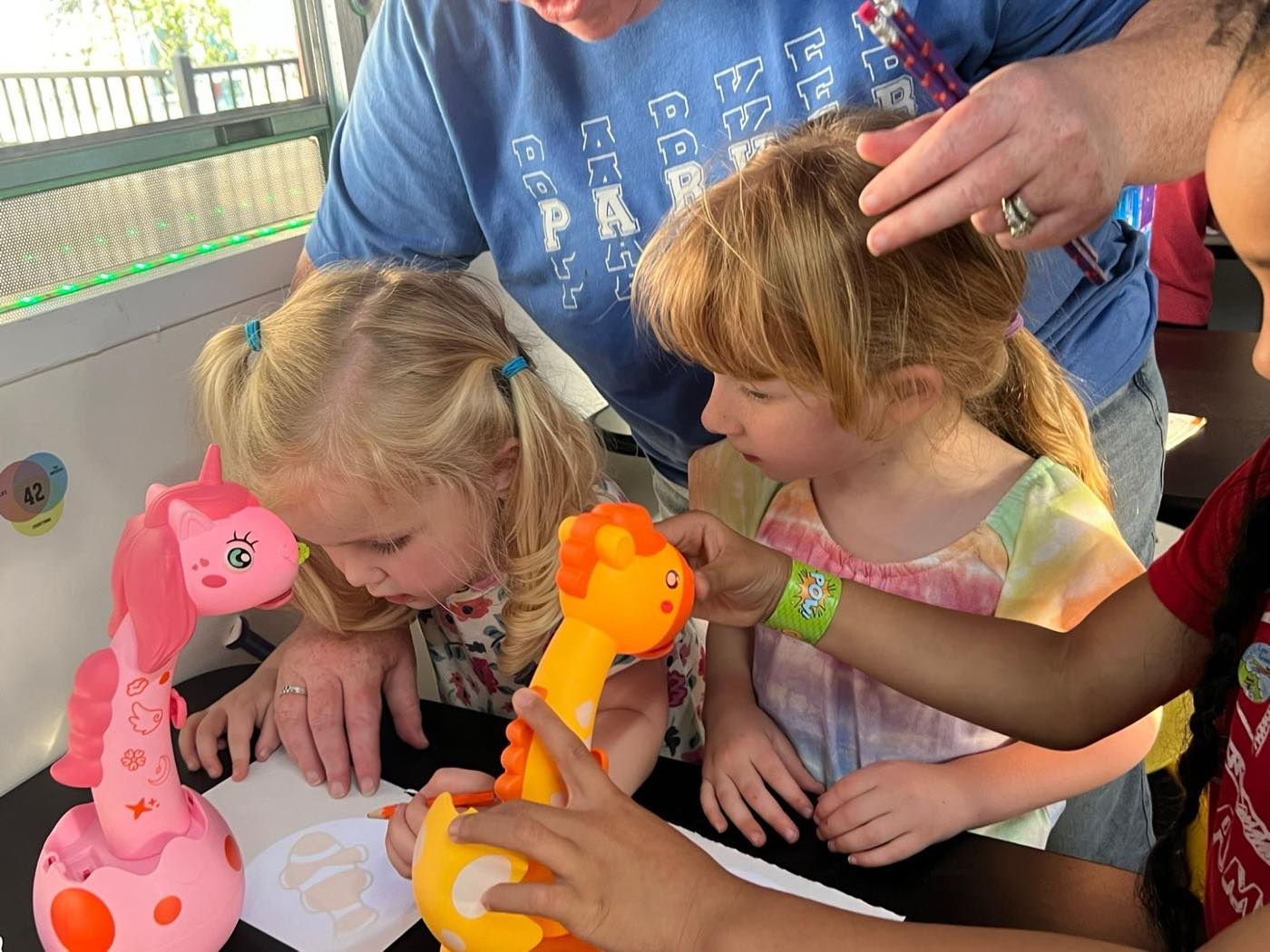 Two students drawing with a group leader during an art and design activity